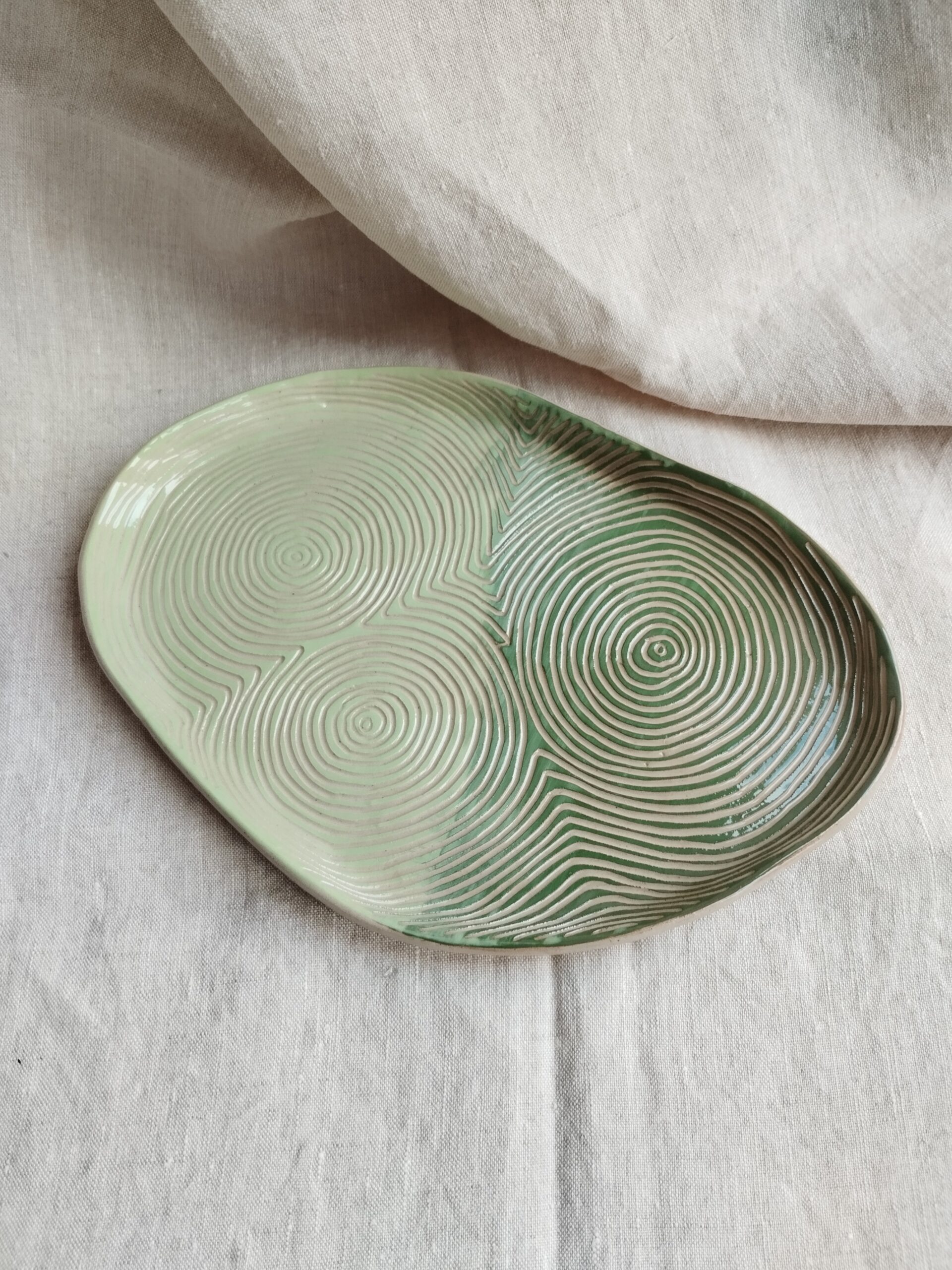 Plat "sillon" rouge vert et amande, en céramique artisanale colorée, gravé de lignes concentriques selon la technique du sgraffito