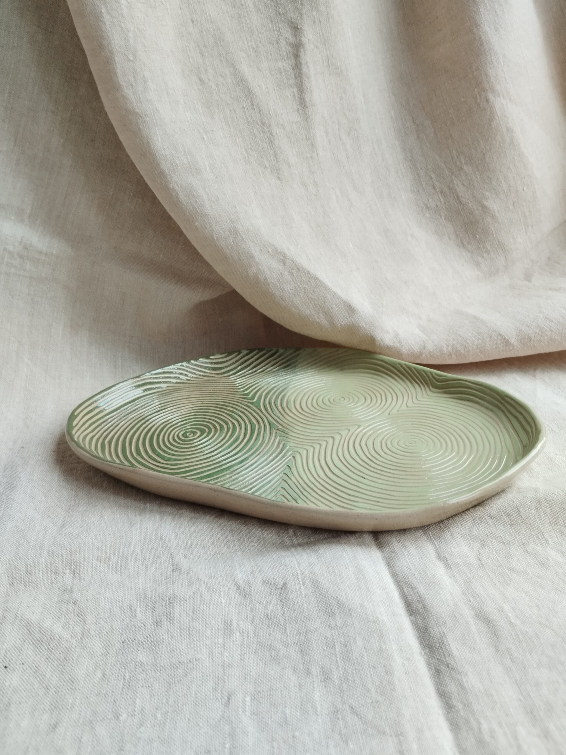Plat "sillon" rouge vert et amande, en céramique artisanale colorée, gravé de lignes concentriques selon la technique du sgraffito