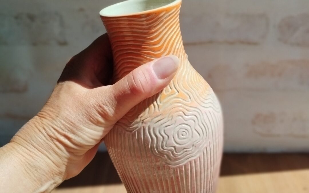 Vase céramique orange et rose avec motif de lignes gravées évoquant des fleurs et des tiges